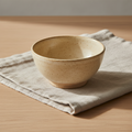 Small ivory speckled stoneware bowl on natural linen and pale wood